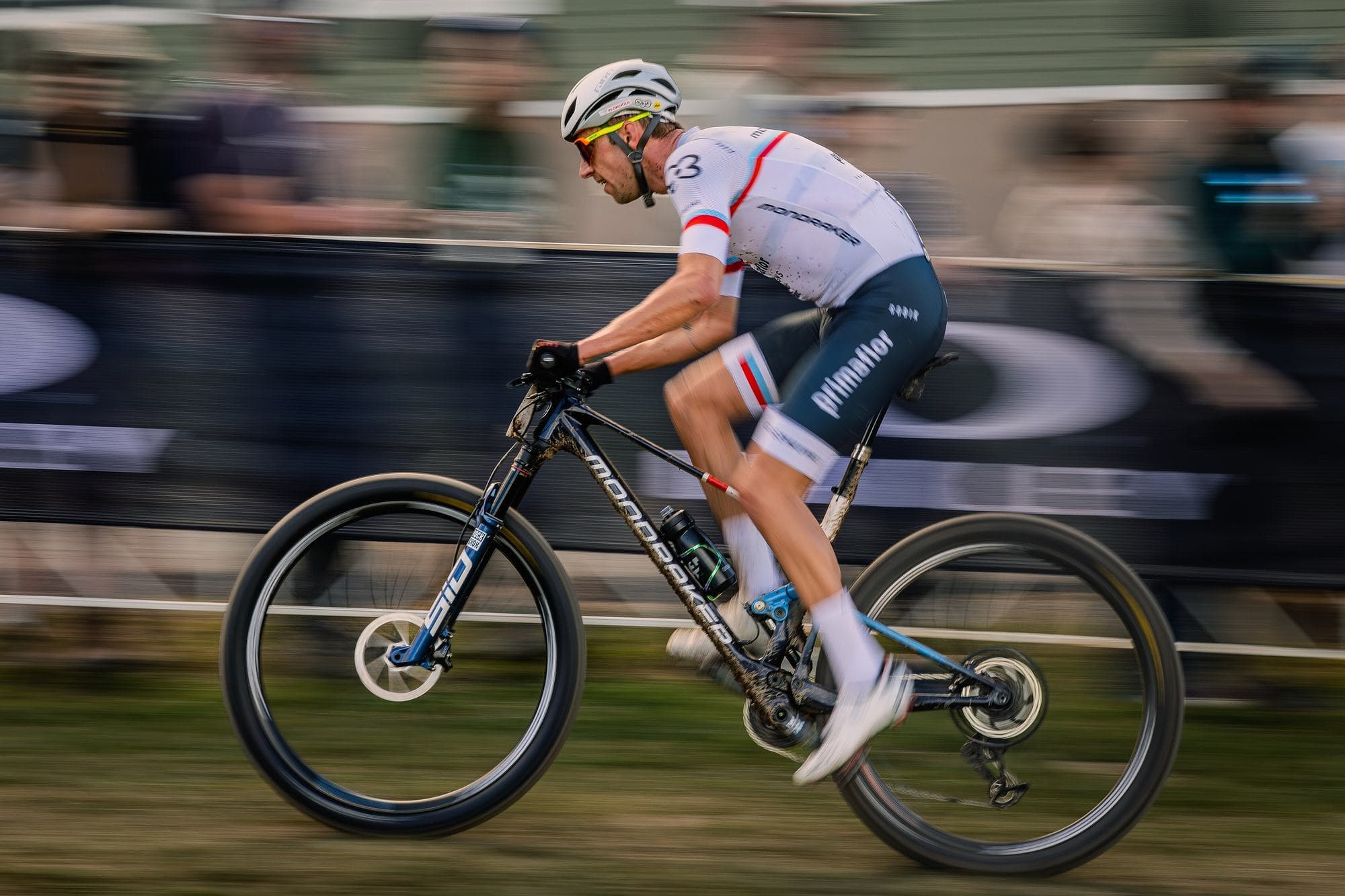 Cross-country mountain bike racer at speed, panned against the crowd at the Snowshoe World Cup